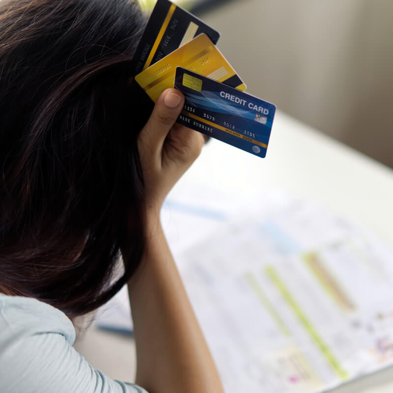 Debt Consolidation Lady looking at bills holding 3 credit cards.