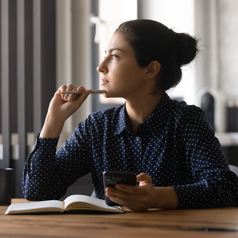 A young lady thinking and writing down goals