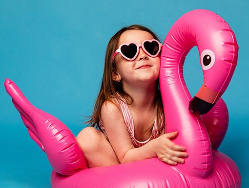A young girl on a pink flamingo floaty